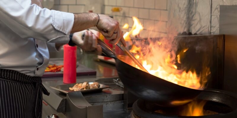 A man cooks cooking deep fryers in a kitchen fire.